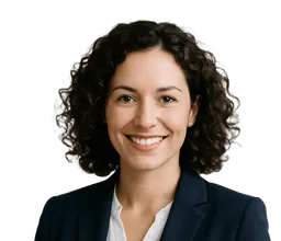 Eine Frau mit dunklen halblangen Locken, dunklem Blazer und weißer Bluse lächelt in die Kamera